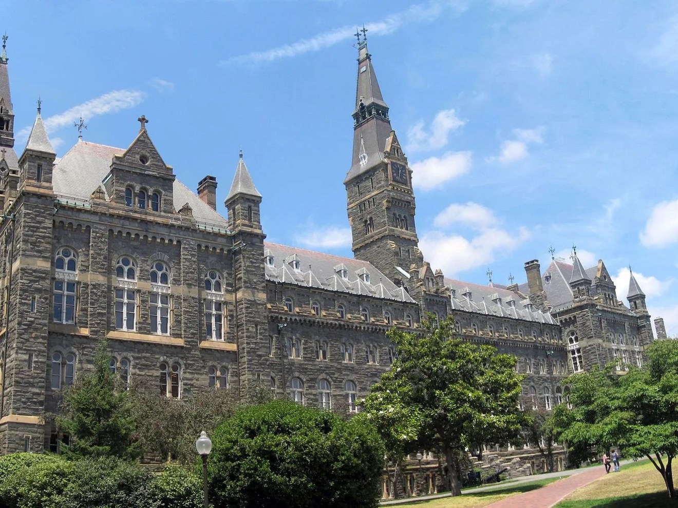 Gothic-style stone building with spires under a blue sky with clouds.