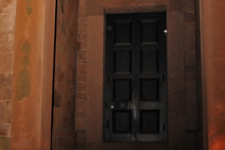 Dark wooden door set in a stone wall with slight shadows.