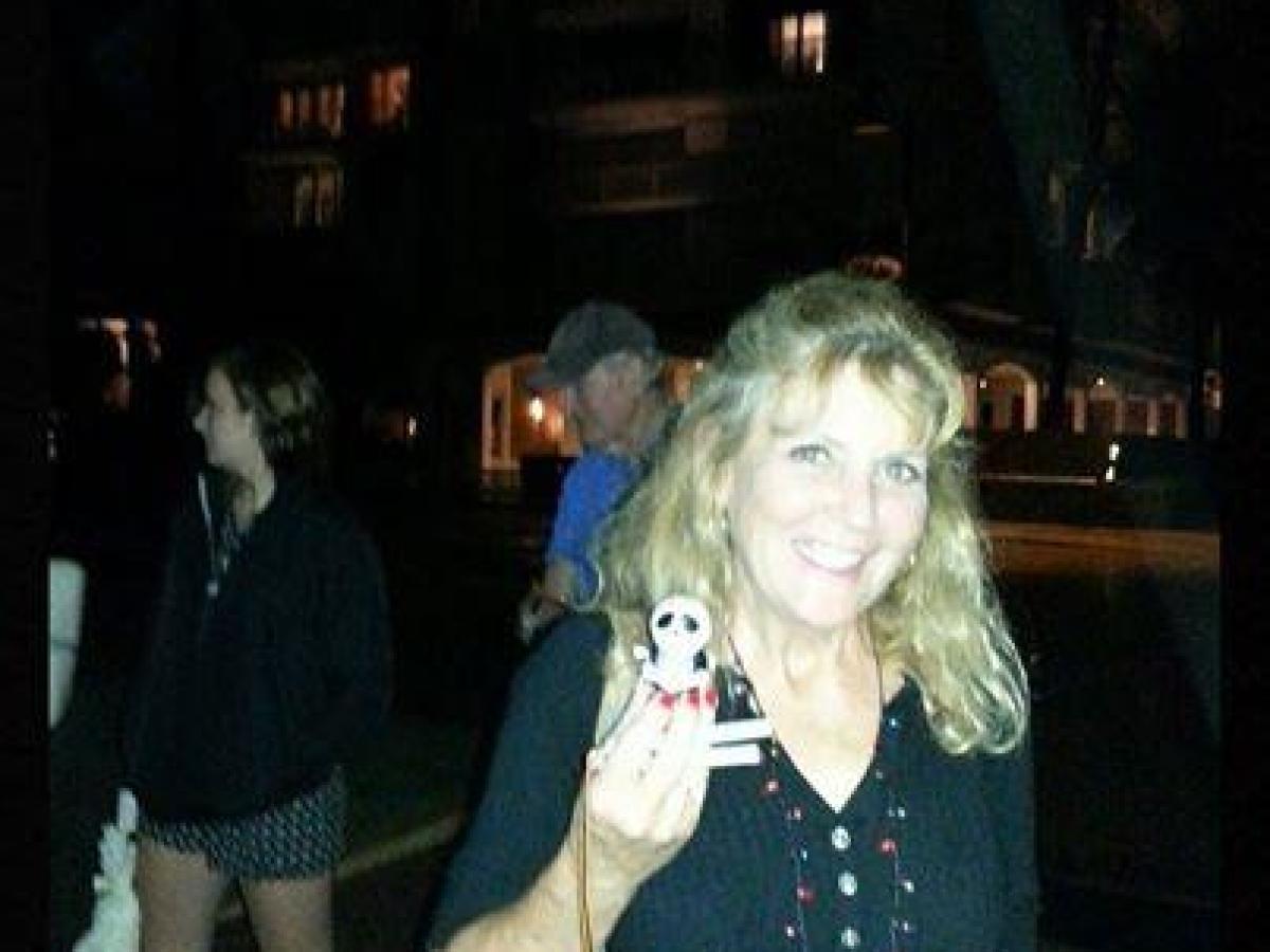 Smiling woman holding a small figure, standing outdoors at night with 'Trivia Winner' text above.