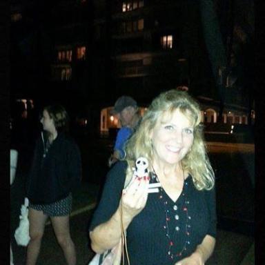 Smiling woman holding a small figure, standing outdoors at night with 'Trivia Winner' text above.