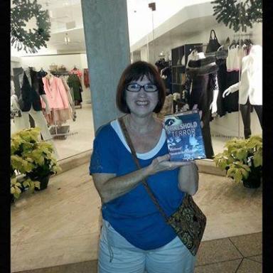 Smiling woman holding book, standing in a mall. Text: Ghosts of Palm Beach Trivia Challenge Winner.