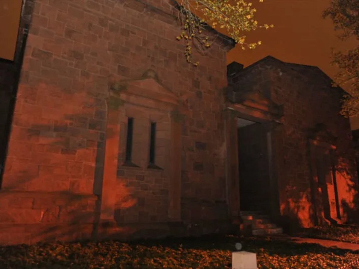 Old stone building at night with orange lighting and dark sky.